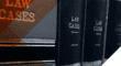 Books of law cases lined on a bookshelf.