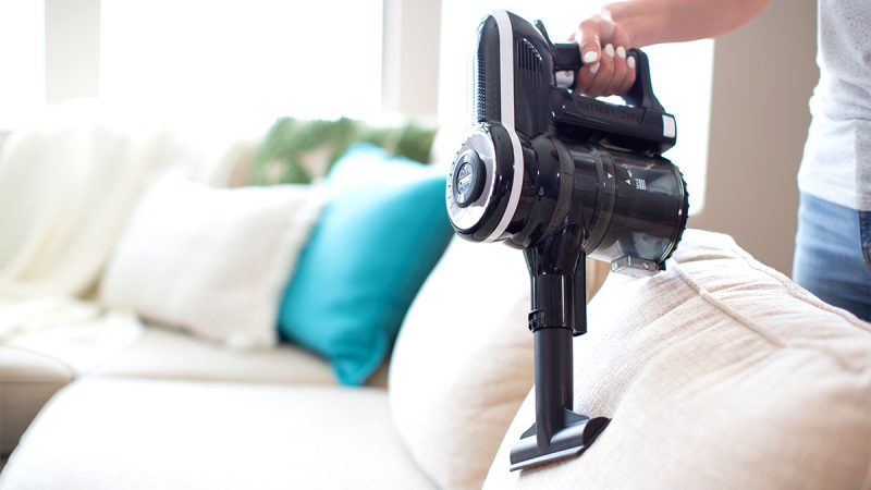 a person vacuuming a couch with a vacuum