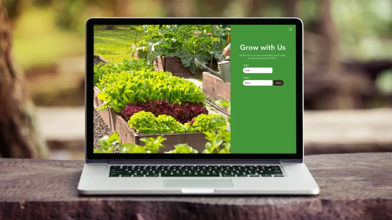 Laptop displaying the STL Composting website with a sign-up form alongside a vibrant vegetable garden, representing residential composting services and sustainable food waste recycling.