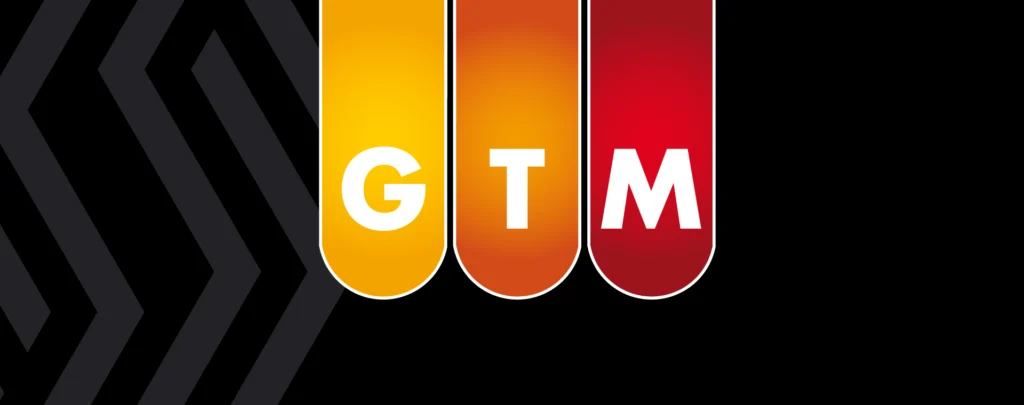 The letters GTM in capital letters on colored banners. The T is on a banner of Timmermann Group orange.