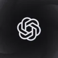 A grayscale illustration featuring the ChatGPT Atlas emblem in the center, set against a dark circular gradient background.