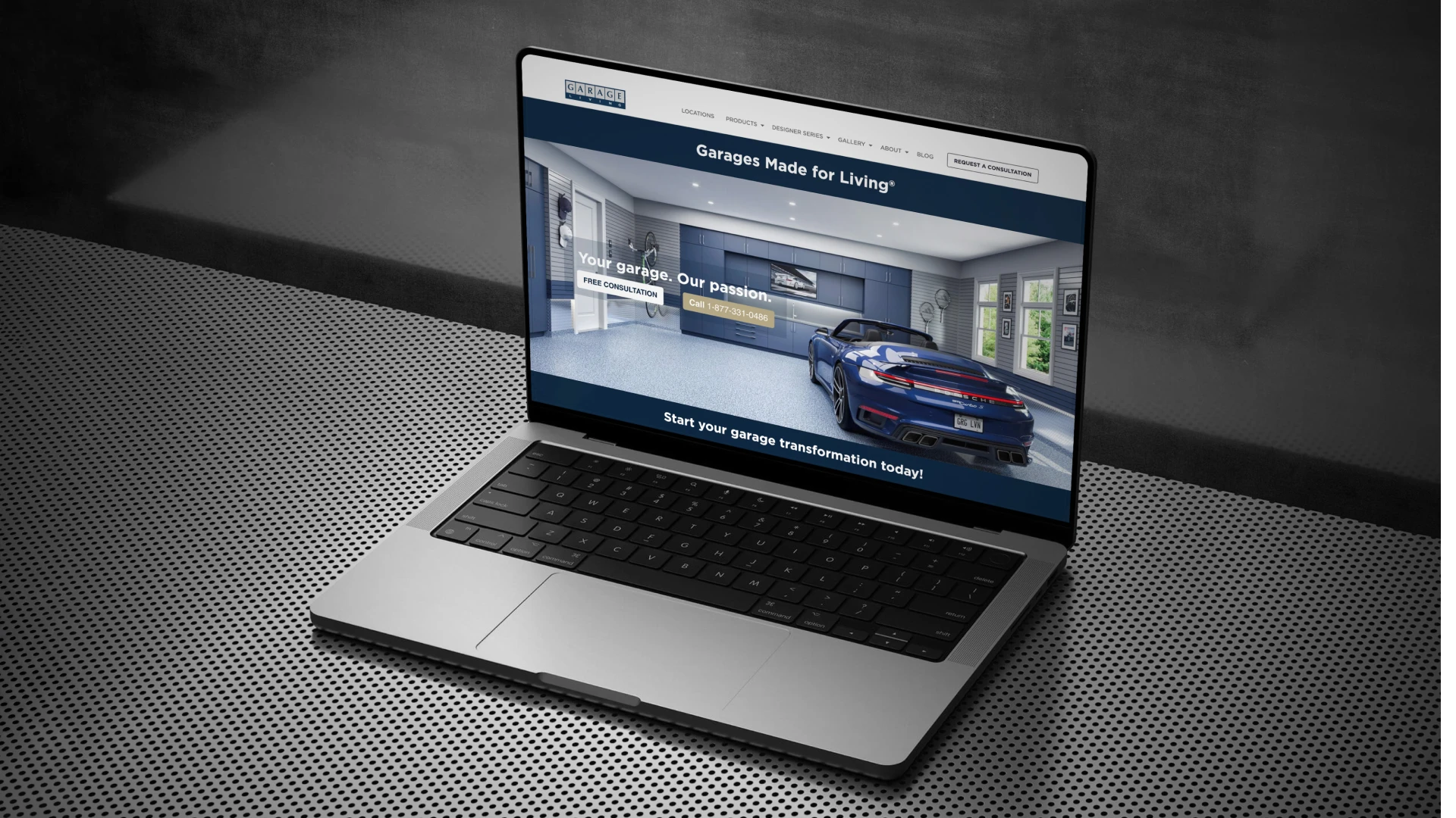A sleek laptop on a perforated metal table displays a website about garage transformations, featuring a modern garage with a sports car inside.