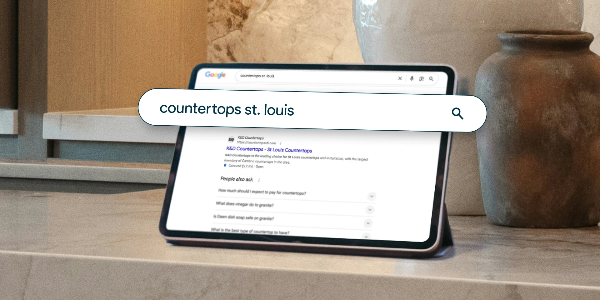 A tablet on a countertop displays a Google search for "countertops st. louis." Next to it is a large ceramic vase, suggesting a kitchen setting.