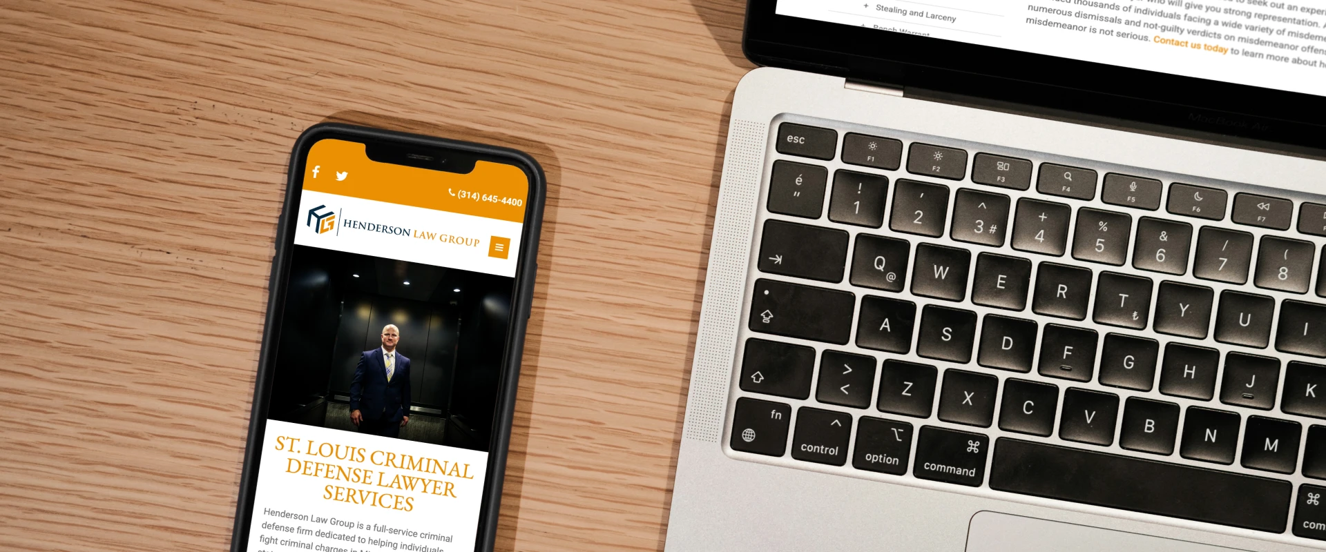 Mobile and desktop views of the Henderson Law Group website displayed on a smartphone and laptop on a wooden desk.